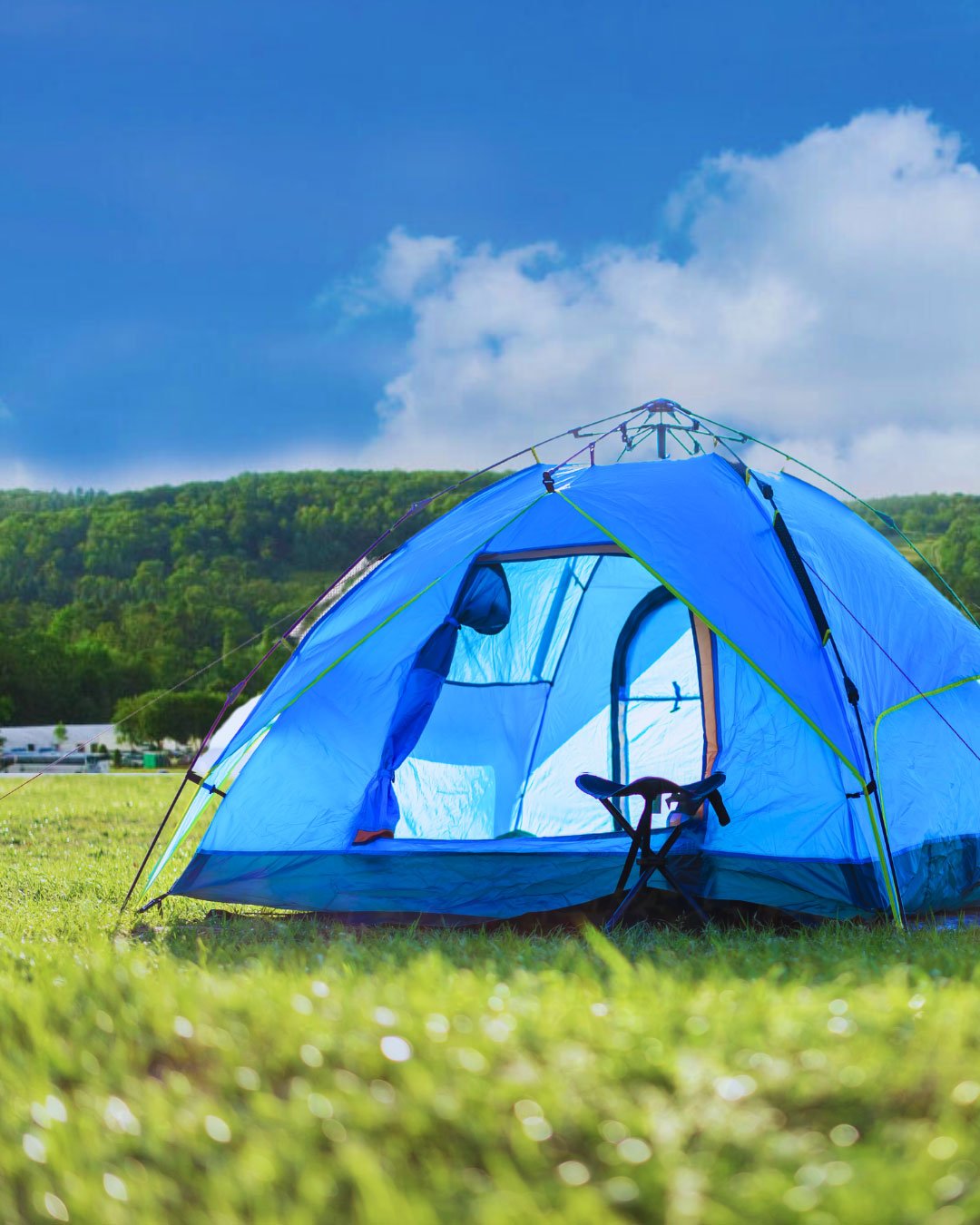 Blue tent in green field with blue sky